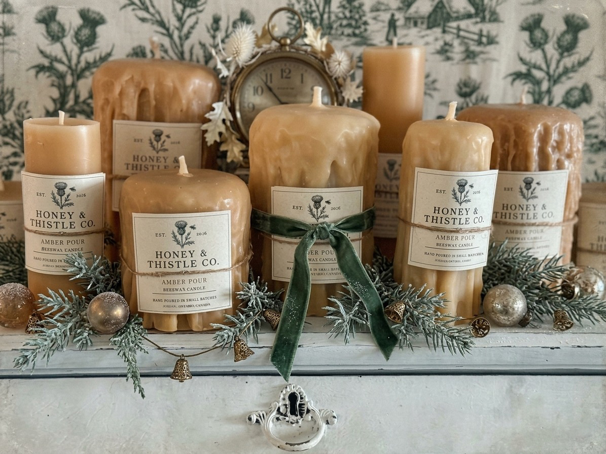 Honey & Thistle Co. Amber Pour beeswax candles with a green velvet bow, evergreen sprigs and gold bells